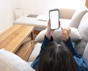 Woman configuring privacy settings on the mobile phone, lying down at home. white screen. "Privacy settings appears on the screen..