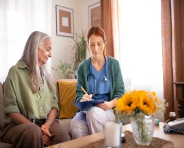 Nurse cosulting with senior woman her health condition at her home.